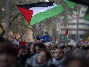 A boy waves a Palestinian flag as demonstrators march during a protest in support of Palestinians and calling for an immediate ceasefire in Gaza, in Barcelona, Spain, on Jan. 20, 2024.