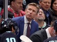Dave Hakstol looks up while Seattle Kraken players gather at the bench