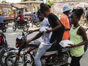 Juliana St. Vil returns with a container of food to the shelter where she now lives with her family after fleeing gang violence in their neighborhood, in Port-au-Prince, Haiti, Wednesday, May 15, 2024.