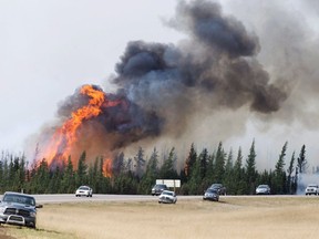 RCMP escort evacuees from Fort McMurray, Alberta past wildfires that were still burning out of control Saturday, May 7, 2016.