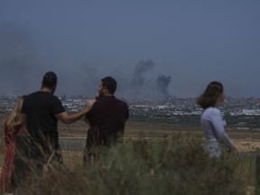 People watch smoke rising to the sky after an explosion in the Gaza Strip, as seen from southern Israel, Friday, May 17, 2024.