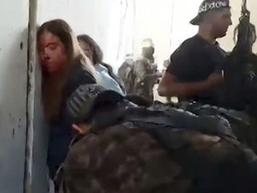 In this image taken from video provided by the Hostage Families Forum, Israeli female soldiers from the Nahal Oz military base are placed against the wall and shackled by members of Hamas after they were taken captive on Oct. 7, 2023.