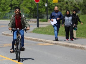 A teenager rides a bike. Three family members are in the background.