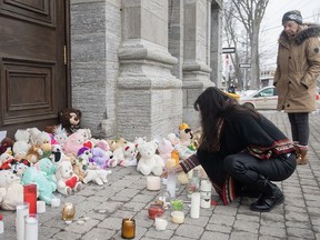A woman lights a candle at a memorial outside a church close to the site of a daycare centre in Laval, Que, Thursday, February 9, 2023, where a bus crashed into the building killing two children. The man accused of murdering two children and injuring six others after a city bus crashed into Montreal-area daycare is scheduled to stand trial over five weeks beginning April 2025.