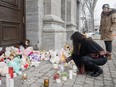 A woman lights a candle at a memorial outside a church close to the site of a daycare centre in Laval, Que, Thursday, February 9, 2023, where a bus crashed into the building killing two children. The man accused of murdering two children and injuring six others after a city bus crashed into Montreal-area daycare is scheduled to stand trial over five weeks beginning April 2025.