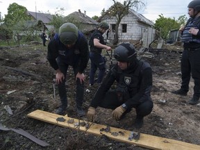 A Ukrainian police officer and war crimes prosecutor inspect fragments of a glide bomb in front of damaged house, after a Russian airstrike on a residential neighbourhood in Kharkiv, Ukraine, Saturday, May 18, 2024.
