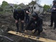 A Ukrainian police officer and war crimes prosecutor inspect fragments of a glide bomb in front of damaged house, after a Russian airstrike on a residential neighbourhood in Kharkiv, Ukraine, Saturday, May 18, 2024.