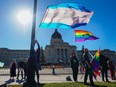 People hold pride flags while attending a rally against the Saskatchewan government's proposed legislation on pronoun policy in front of the provincial legislature in Regina, Tuesday, Oct. 10, 2023.