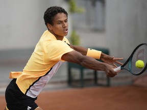Tennis player in yellow returns a shot