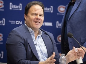 Canadiens executive vice-president of hockey operations Jeff Gorton is wearing an open-collared shirt and blue jacket while sitting at a table during a news conference.