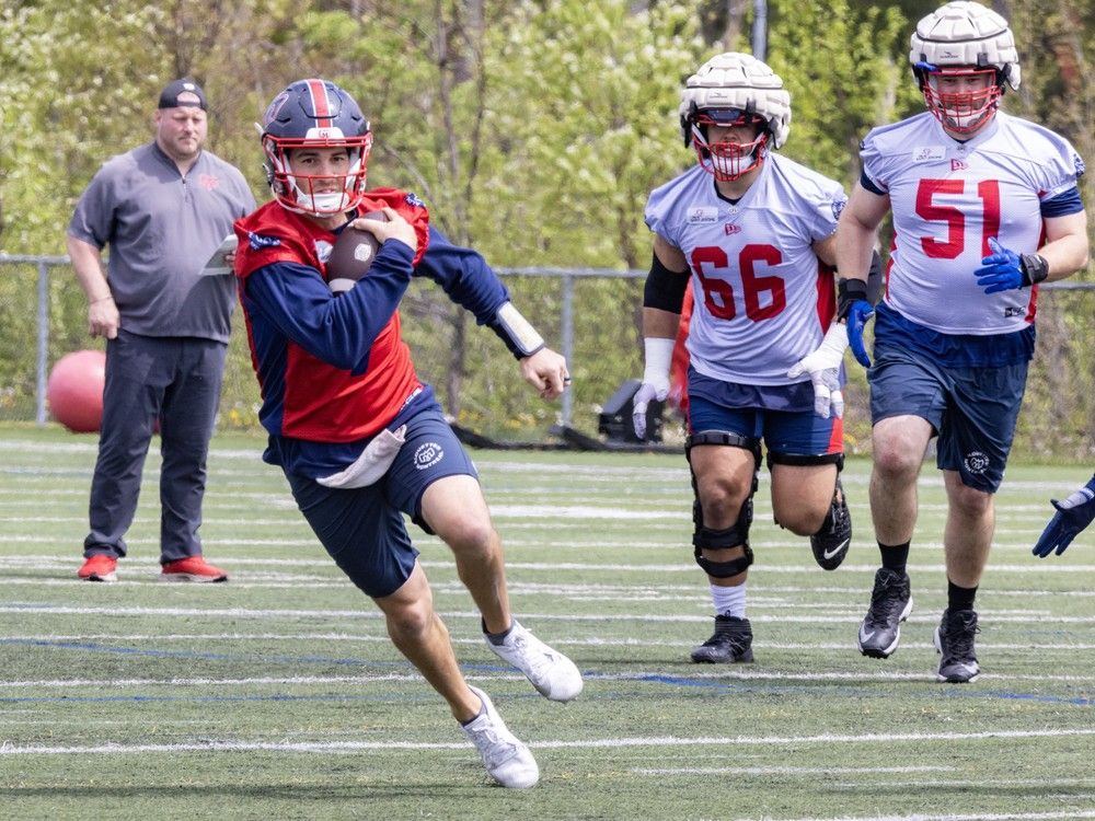 Quarterback Cody Fajardo runs with the ball through a hole opened by offensive linemen Pier-Olivier Lestage and Kristian Matte, right, during Alouettes training camp practice in St-Jérôme on Thursday May 16, 2024.