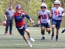 Quarterback Cody Fajardo runs with the ball through a hole opened by offensive linemen Pier-Olivier Lestage and Kristian Matte, right, during Alouettes training camp practice in St-Jérôme on Thursday May 16, 2024.