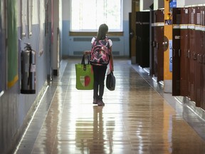 A child seen from behind walks along a school hallway.