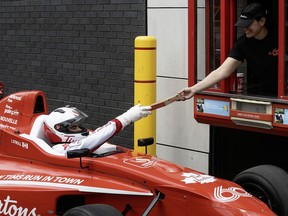 Montreal native and F1 driver Lance Stroll is seen inside his red Aston Martin car getting a Tim Hortons pizza from a drive-thru window during a promotional event.