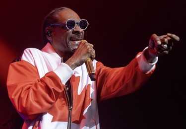 Snoop Dogg, wearing a partially zipped Canadian flag jacket, gesticulates as he performs