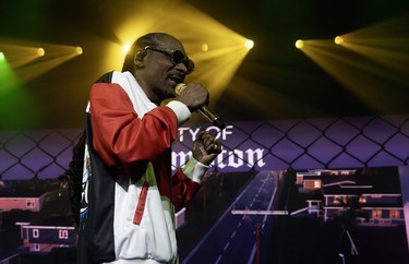 Snoop Dogg rapping on stage stage in front of a projected illustration of Compton