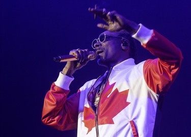 Snoop Dogg, wearing a partially zipped Canadian flag jacket, gesticulates as he performs