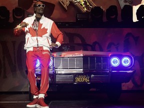 Snoop Dogg performs on stage in a Canadian flag outfit in front of an old Chevrolet convertible