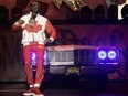 Snoop Dogg performs on stage in a Canadian flag outfit in front of an old Cadillac convertible