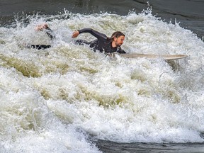 A man paddles his surfboard in churning water.