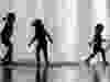 The silhouettes of three children are seen in a water fountain.