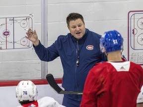 Laval Rocket head coach Jean-François Houle is seen with his right arm in the air and an hockey rink diagram behind him as he faces players and gives them instructions during Canadiens rookie camp last year.