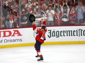 A hockey player lifts the Stanley Cup toward the crowd.
