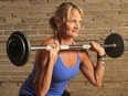 A woman lifts weights in front of a brick wall