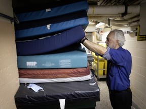 A man shifts hospital mattresses that are stacked in a hallway.