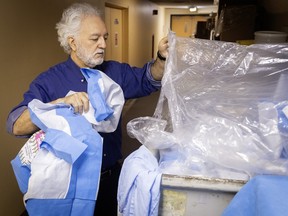 A man recovers single-use sheets from a garbage bin.