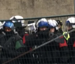 A police officer points a tear gas gun at protesters