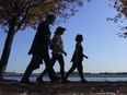 People are seen in silhouette while walking along the shore of a lake