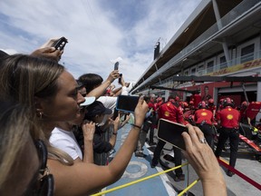 Race fans take photos of Ferrari mechanics in paddock