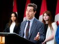 Liberal MP Anthony Housefather speaks at a podium with Canadian flags in the background.