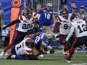 The ball is seen popping free as Alouettes' Darnell Sankey wraps up Blue Bombers' Nic Demski in a tackle as three other Alouettes defenders hover around the play.