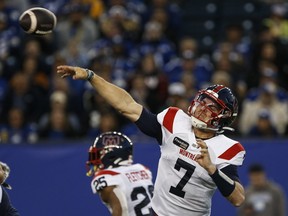 Alouettes quarterback Cody Fajardo, in a white jersey with red and blue trim, is seen grimacing with effort after releasing a pass. The ball can be seen just above his extended right arm.