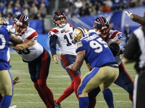 A player in a white Alouettes jersey looks up while teammates block players in blue and gold