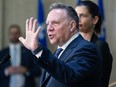 François Legault holds his hand up, palm facing out, while speaking
