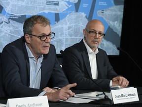 Two men sit at a table for a news conference with a map behind them