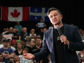 Conservative Leader Pierre Poilievre, with a microphone in his left hand is seen speaking at a rally in Montreal with the Canadian and Quebec flags sen behind an adoring crowd behind him.