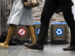 People walk past waste and recycling bins in the Montreal métro.