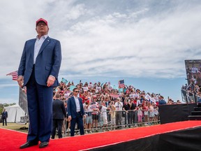 Former U.S. president Donald Trump stands wearing a red hat