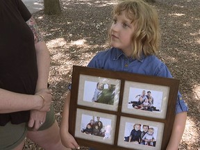 Olive Wilson shows off her family photo as she plays at a park on Friday, June 14, 2024.