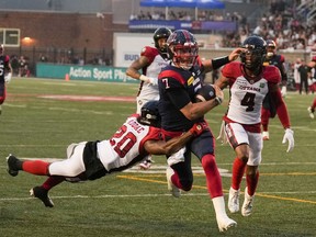 Alouettes quarterback Cody Fajardo, in blue jersey with red trim, is tackled around the waist by leaping Redblacks defensive-back Alonzo Addae during game last week at Molson Stadium.