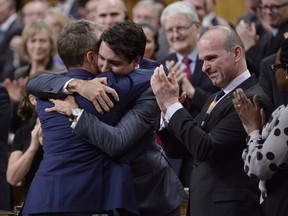 Prime Minister Justin Trudeau hugs Veteran's Affairs Minister Seamus O'Regan after making a formal apology to individuals harmed by federal legislation, policies, and practices that led to the oppression of and discrimination against LGBTQ2 people in Canada, in the House of Commons in Ottawa, Tuesday, Nov. 28, 2017.