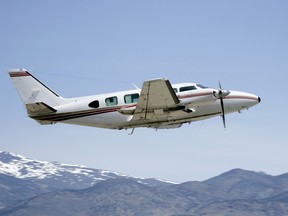 A small plane is seen in the sky with mountains in the background