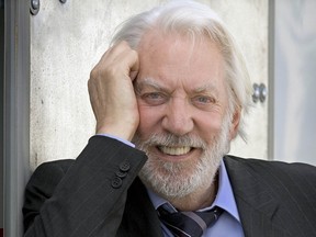 Donald Sutherland smiles while holding his hand against his face