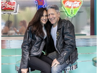 A man and woman pose at the counter of a '50s-style diner.