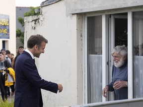 French President Emmanuel Macron, left, meets a resident, Tuesday, June 18, 2024, on the Île de Sein, Brittany. The early legislative vote June 30 and July 7 was triggered by Emmanuel Macron's decision last Sunday to dissolve the National Assembly, France's lower house of parliament, after his centrist party suffered a crushing defeat by the National Rally in the election for the European Parliament.