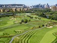 A golf course seen from above with Montreal's city skyline in the background